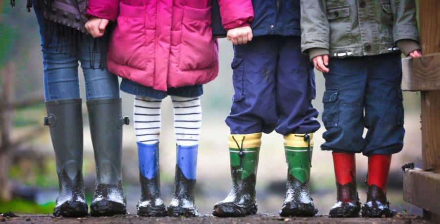 4 Kinder in gummistiefel stehen nebeneinander.