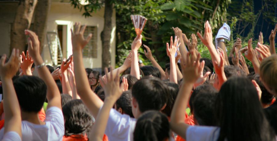 Viele Kinder mit Handzeichen vor einem Gebäude. Foto: unplash.